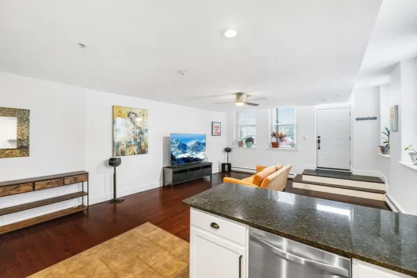 a kitchen with stainless steel appliances granite countertop a stove and white cabinets with wooden floor