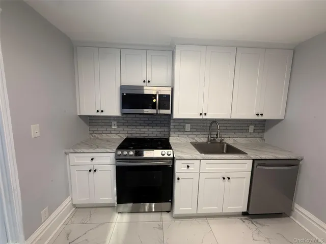 a kitchen with white cabinets and appliances