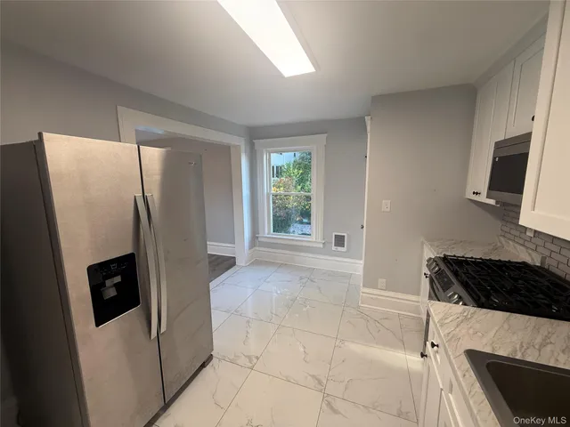 a kitchen with a refrigerator a stove a microwave and a window