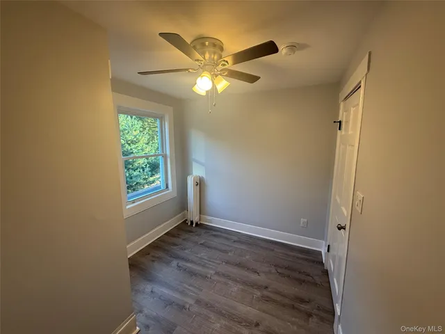 a view of an empty room with window and chandelier fan