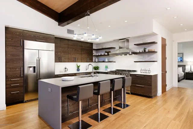a kitchen with stainless steel appliances granite countertop a kitchen island a stove a refrigerator and a sink