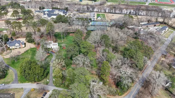 an aerial view of residential house with outdoor space and trees all around