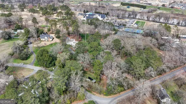 a view of a white house next to a yard with big trees