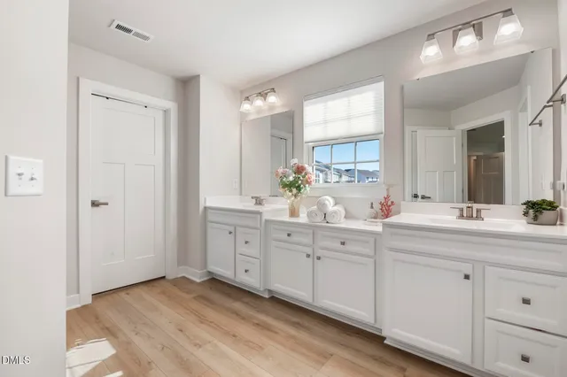 a spacious bathroom with double sink large mirror and a window