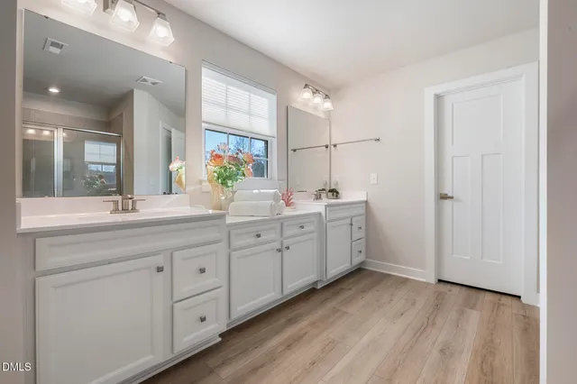 a spacious bathroom with a double vanity sink a mirror and a shower