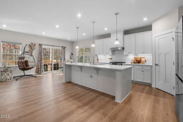 a large white kitchen with lots of counter space a sink appliances and cabinets