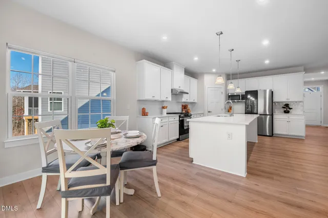 a kitchen with a dining table chairs refrigerator and wooden cabinets