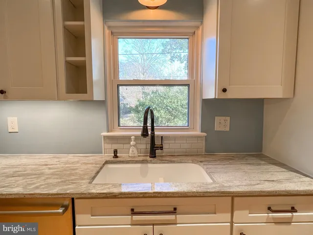 a kitchen with granite countertop white cabinets and a window