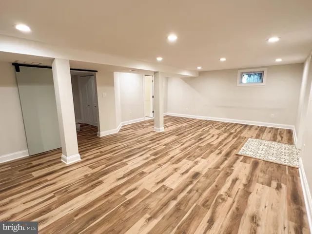 an empty room with wooden floor and bathroom view