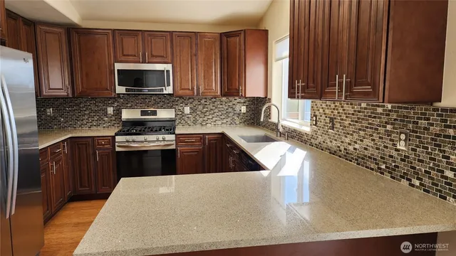 a kitchen with stainless steel appliances granite countertop a refrigerator stove and microwave