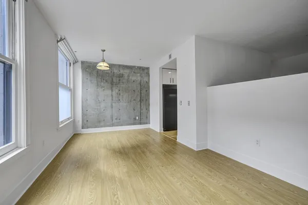 a view of an empty room with wooden floor and a window