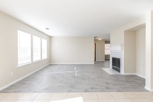 an empty room with windows and fireplace