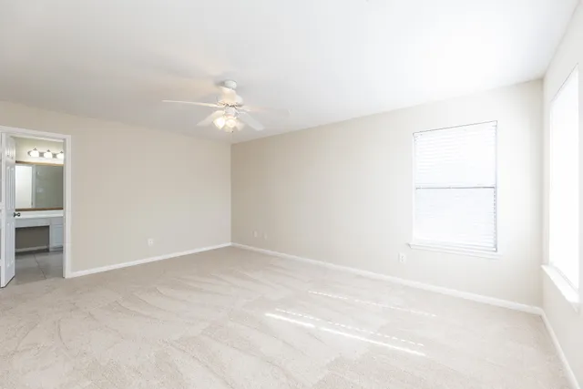 an empty room with a window and a ceiling fan