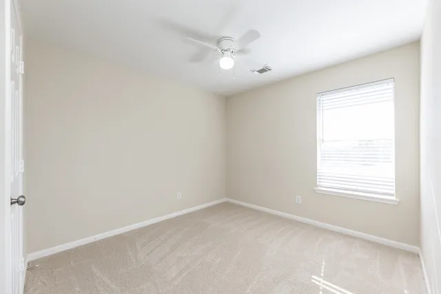 an empty room with a window and a fan
