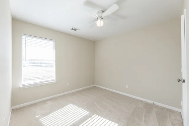 an empty room with a window and a ceiling fan