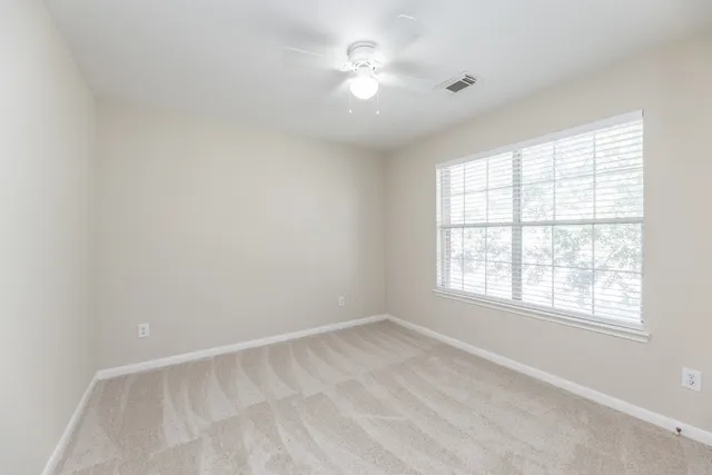 an empty room with a window and a fan