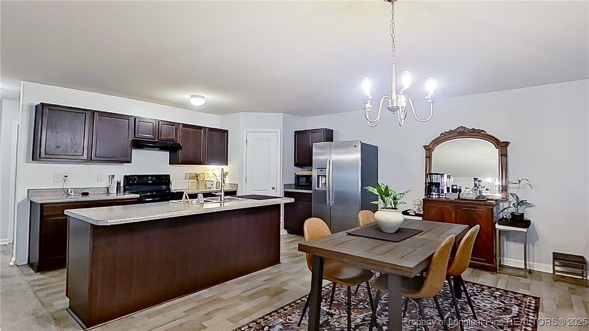 29 York Court Spring Lake, NC 28390 - Photo 11 of 22 a kitchen with stainless steel appliances kitchen island granite countertop a dining table chairs stove refrigerator and microwave