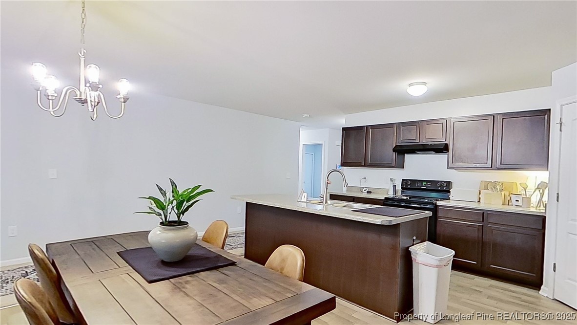 29 York Court Spring Lake, NC 28390 - Photo 12 of 22 a kitchen with stainless steel appliances granite countertop a sink a stove a dining table and chairs with wooden floor