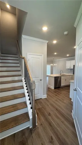 a view of a living room with wooden floor and a kitchen view