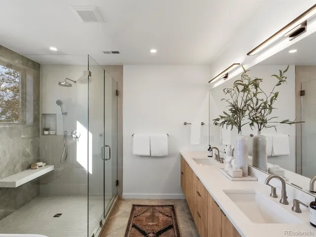 a bathroom with a double vanity sink mirror and shower