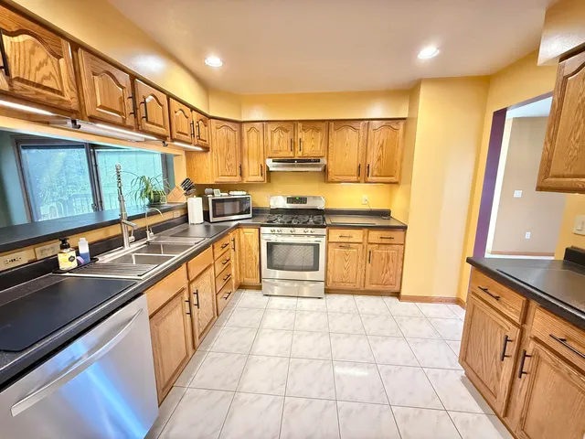 a large kitchen with stainless steel appliances granite countertop a sink and cabinets