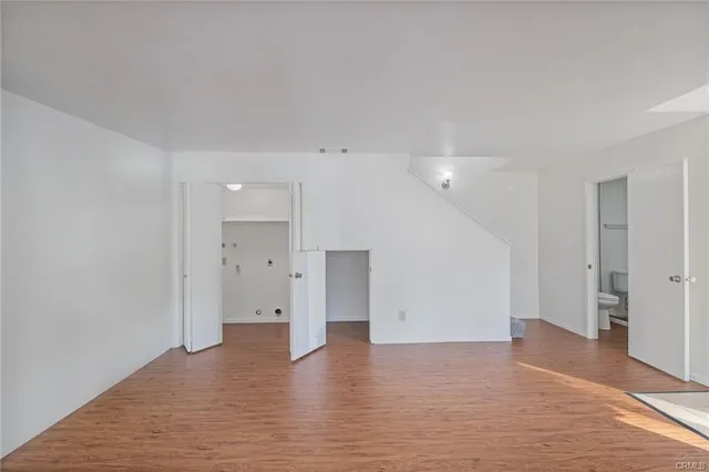 a view of an empty room with wooden floor and closet