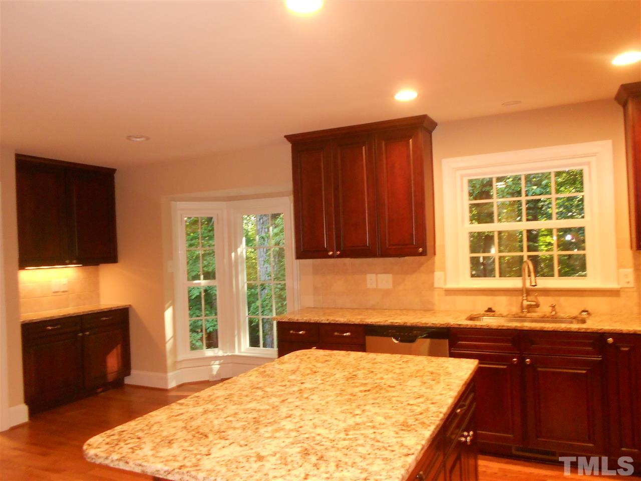 1208 Bancroft Street Raleigh, NC 27612 - Photo 12 of 22 a kitchen with granite countertop wooden cabinets a stove and a sink