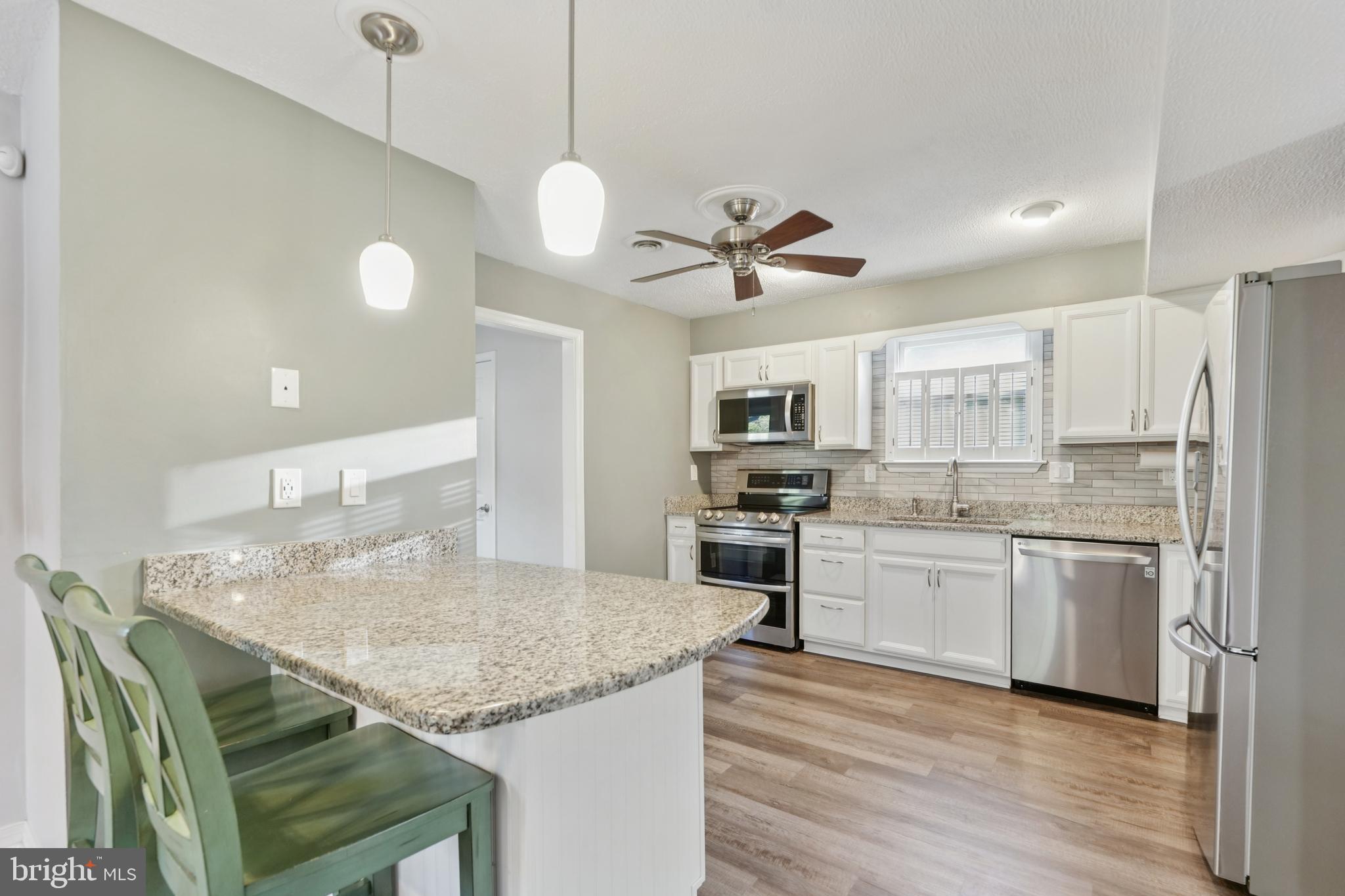 2105 Silver Lane Road Baltimore, MD 21221 - Photo 16 of 55 a kitchen with stainless steel appliances granite countertop a sink a stove a refrigerator and island with wooden floor