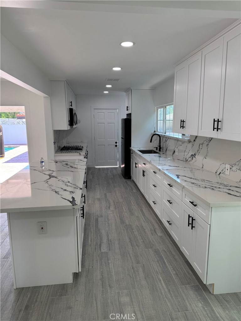 5230 Seville Avenue Encino, CA 91316 - Photo 21 of 61 a large kitchen with a stove a sink dishwasher and a refrigerator with wooden floor