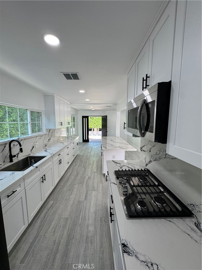 5230 Seville Avenue Encino, CA 91316 - Photo 59 of 61 a kitchen with stainless steel appliances a sink stove and wooden floor