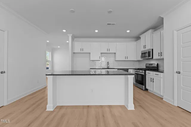 a kitchen with granite countertop white cabinets and stainless steel appliances