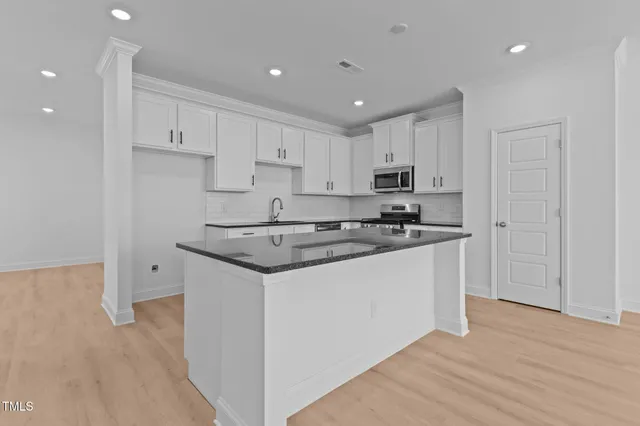 a kitchen with granite countertop white cabinets and stainless steel appliances