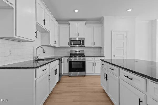 a kitchen with granite countertop white cabinets and wooden floor
