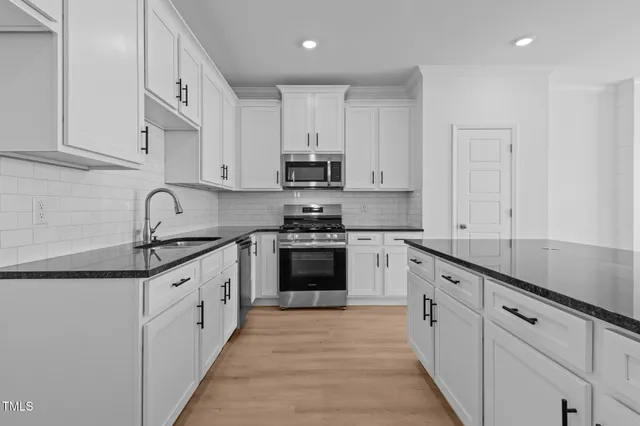 a kitchen with granite countertop white cabinets and wooden floor