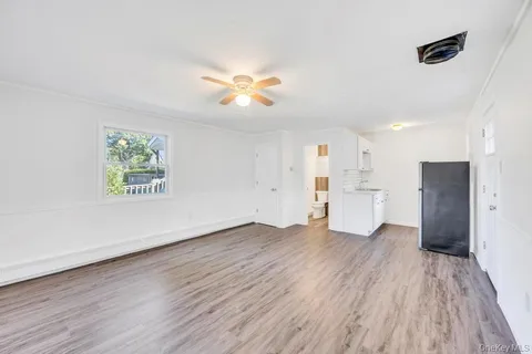 a view of empty room with wooden floor and window