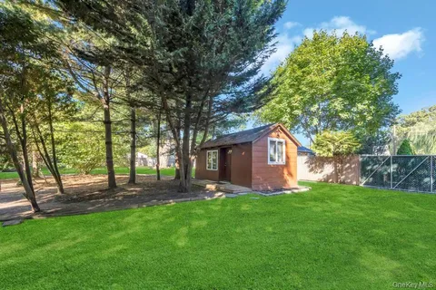 a view of a backyard with large trees and wooden fence