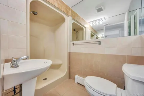 a bathroom with a sink a toilet a mirror and shower