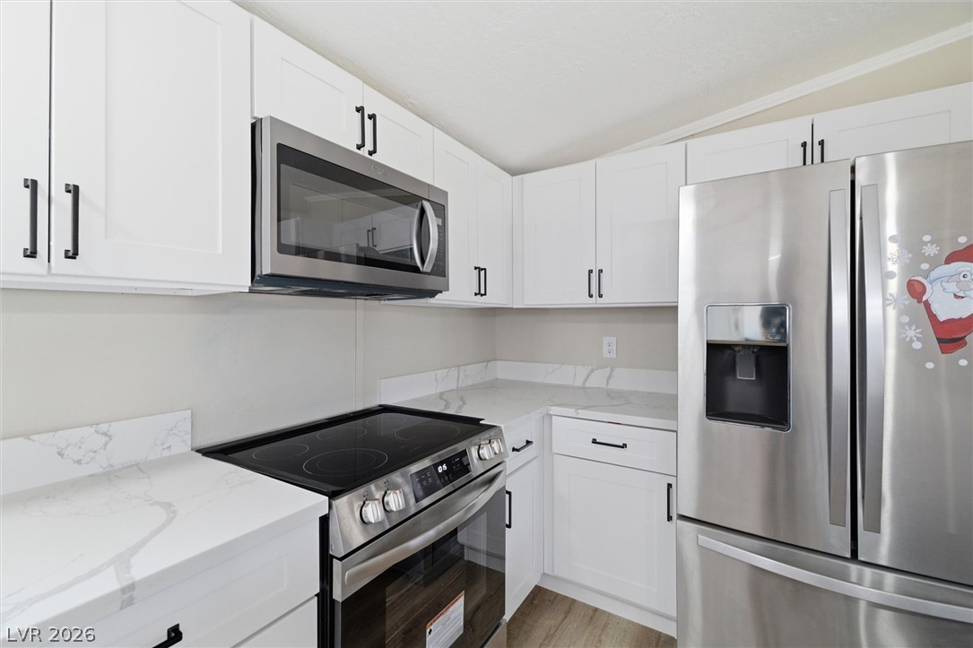4331 Retread Road Pahrump, NV 89048 - Photo 9 of 31 Culinary delights await in this modern kitchen, showcasing sleek white cabinetry and stainless steel appliances.