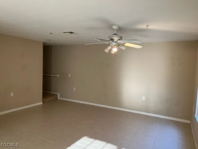 an empty room with a ceiling fan and a window
