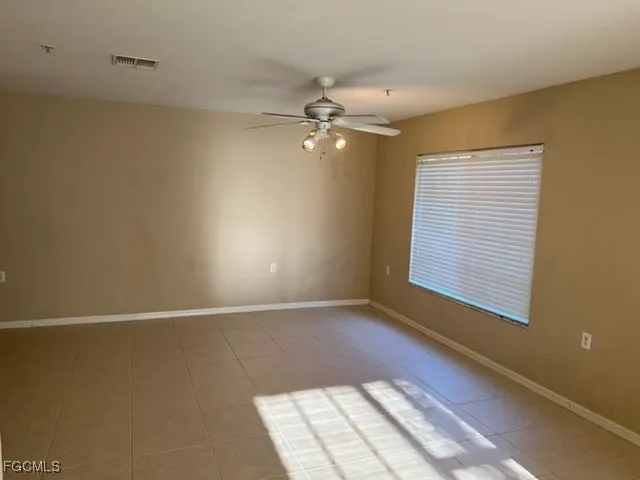 an empty room with windows and fan