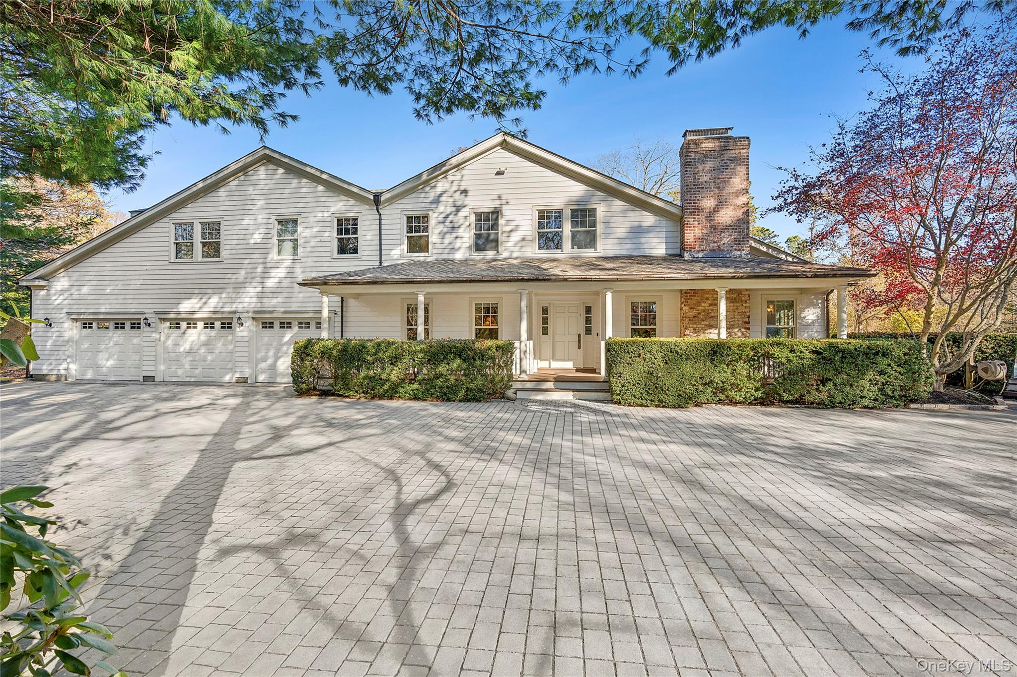 View of front of house with a chimney, decorative driveway, covered porch, and an attached garage
