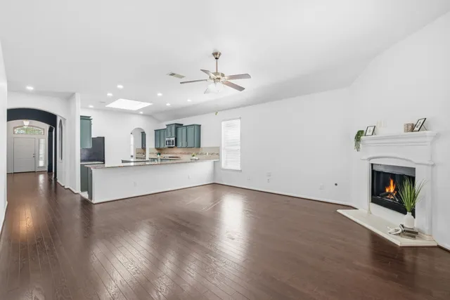 an empty room with wooden floor fireplace and windows
