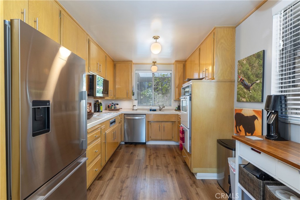 2772 2nd Street, Unit 2G Long Beach, CA 90803 - Photo 12 of 53 a kitchen with a refrigerator a sink dishwasher a stove and a dining table with wooden floor