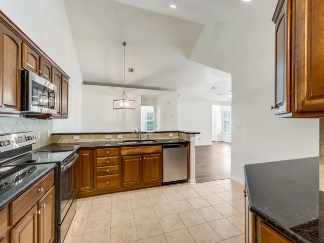 a kitchen with stainless steel appliances granite countertop a stove a sink and a microwave