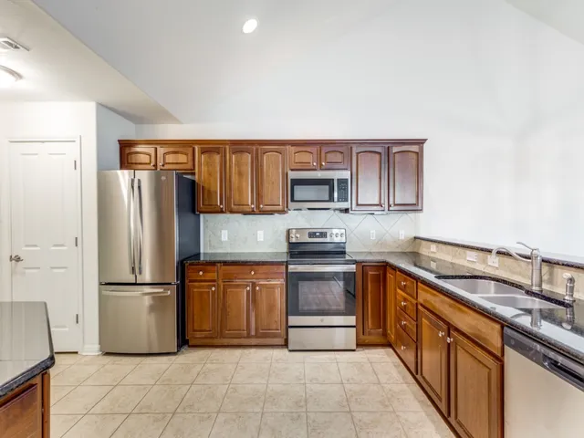 a kitchen with stainless steel appliances granite countertop a refrigerator sink and stove