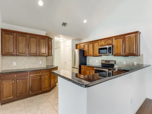 a kitchen with stainless steel appliances granite countertop a sink stove and microwave