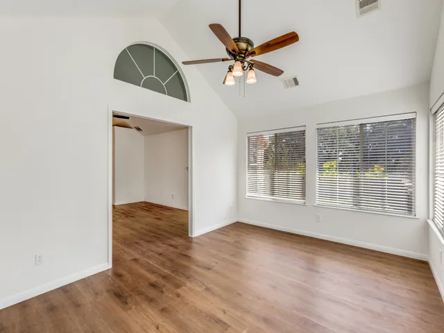 a view of an empty room with wooden floor and a window