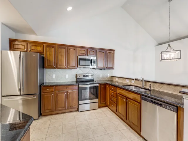 a kitchen with stainless steel appliances granite countertop a refrigerator sink and stove