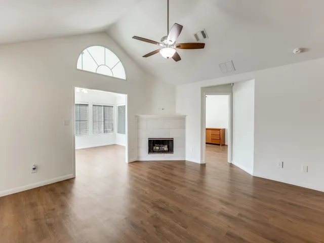 an empty room with wooden floor fireplace and windows