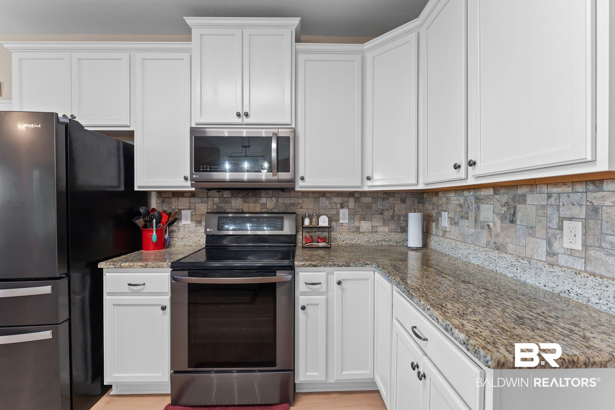 28980 Comstock Road Elberta, AL 36530 - Photo 8 of 38 Kitchen featuring stainless steel appliances, white cabinets, tasteful backsplash, and dark stone counters